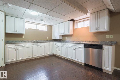 Kitchen featuring a drop ceiling, healthy amount of natural light, white cabinetry, dishwasher, and dark wood-style floors - 4631 43 Avenue, Edmonton, AB - Indoor Photo Showing Kitchen With Upgraded Kitchen