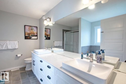 Full bath with a shower stall, double vanity, and dark tile patterned floors - 19633 26A Av, Edmonton, AB - Indoor Photo Showing Bathroom