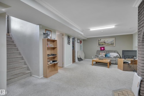 Living room with ornamental molding, light carpet, and stairway - 5312 36 Ave, Wetaskiwin, AB - Indoor Photo Showing Basement
