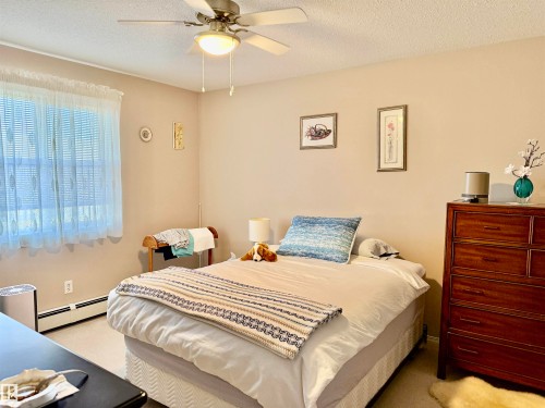 Carpeted bedroom featuring a textured ceiling, a baseboard radiator, and a ceiling fan - 415 4700 43 Avenue, Stony Plain, AB - Indoor Photo Showing Bedroom
