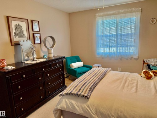 Bedroom with light carpet and a textured ceiling - 415 4700 43 Avenue, Stony Plain, AB - Indoor Photo Showing Bedroom