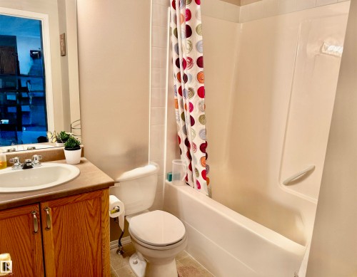 Full bath featuring shower / bath combo with shower curtain, vanity, and tile patterned floors - 415 4700 43 Avenue, Stony Plain, AB - Indoor Photo Showing Bathroom