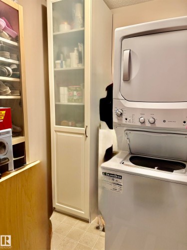Laundry area with light tile patterned flooring and estacked washer and dryer - 415 4700 43 Avenue, Stony Plain, AB - Indoor Photo Showing Laundry Room