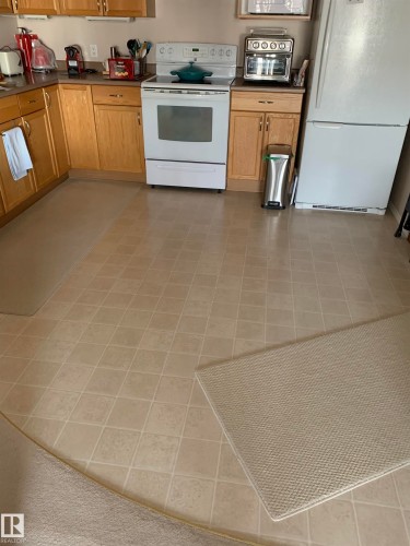 Kitchen with white appliances, dark countertops, and wood finish cabinets - 415 4700 43 Avenue, Stony Plain, AB - Indoor Photo Showing Kitchen
