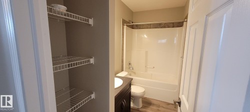Full bath with vanity, washtub / shower combination, wood finished floors, and a closet - 196, 142 Selkirk Place, Leduc, AB - Indoor Photo Showing Bathroom