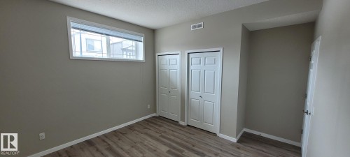 Unfurnished bedroom with two closets, a textured ceiling, and light wood-style floors - 196, 142 Selkirk Place, Leduc, AB - Indoor Photo Showing Other Room