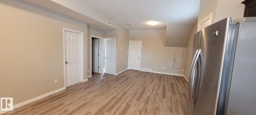 Kitchen featuring freestanding refrigerator, light wood-type flooring, and a textured ceiling - 196, 142 Selkirk Place, Leduc, AB - Indoor Photo Showing Other Room
