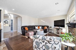 Living area featuring wood-type flooring, a textured ceiling, arched walkways, recessed lighting, and a stone fireplace - 