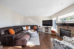 Living area featuring dark wood-type flooring, recessed lighting, a stone fireplace, and a textured ceiling - 