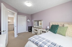 Bedroom featuring light colored carpet, a textured ceiling, a closet, and a chandelier - 