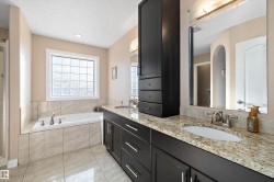 Bathroom with light tile patterned floors, double vanity, and a bath - 