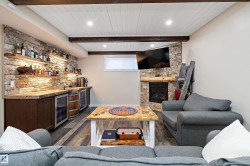Living room featuring beverage cooler, dark wood-style flooring, a fireplace, wet bar, and recessed lighting - 