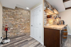 Indoor wet bar featuring open shelves, dark wood-style flooring, and dark brown cabinets - 