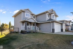 View of front facade with stone siding, a porch, driveway, and an attached garage - 