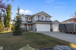 View of front of house featuring stone siding, driveway, an attached garage, a porch, and roof with shingles - 