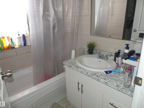 Full bath with vanity, shower / tub combo, tile walls, and decorative backsplash - 10618 96 Street Nw, Edmonton, AB - Indoor Photo Showing Bathroom