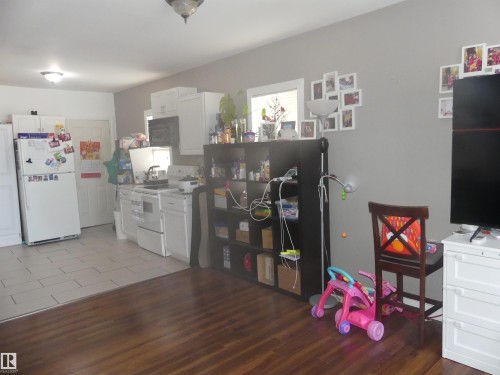 Kitchen featuring white appliances, white cabinetry, and light wood-style flooring - 10618 96 Street Nw, Edmonton, AB - Indoor Photo Showing Kitchen