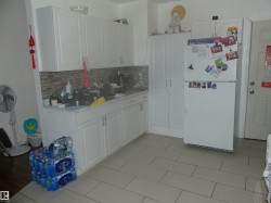 Kitchen featuring light countertops, freestanding refrigerator, white cabinetry, decorative backsplash, and light tile patterned floors - 