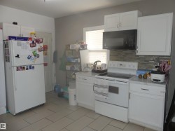 Kitchen featuring white appliances, light countertops, white cabinets, and tasteful backsplash - 