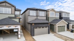View of front of home with a shingled roof, stone siding, and a garage - 