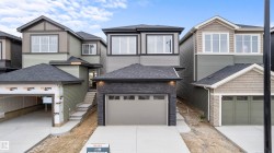 View of front of house featuring a shingled roof, driveway, and stone siding - 
