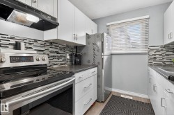 Kitchen with stainless steel range with electric stovetop, range hood, decorative backsplash, white cabinetry, and a textured ceiling - 