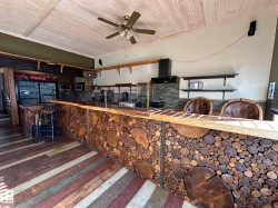 Kitchen with wood ceiling, wall chimney range hood, wall oven, black refrigerator, and ceiling fan - 