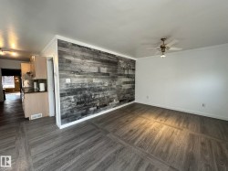Spare room with dark wood-style flooring, crown molding, wooden walls, and a ceiling fan - 