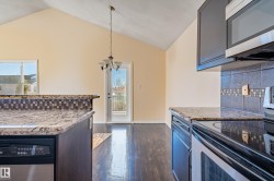 Kitchen with tasteful backsplash, appliances with stainless steel finishes, light stone countertops, pendant lighting, and dark wood finished floors - 