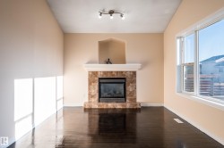 Unfurnished living room featuring a tiled fireplace and dark wood-style flooring - 