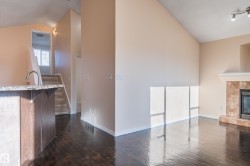 Unfurnished living room with lofted ceiling, a tile fireplace, and dark wood-type flooring - 
