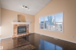 Unfurnished living room with a tiled fireplace, dark wood-style flooring, and vaulted ceiling - 