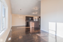 Unfurnished living room featuring a chandelier, dark wood-type flooring, and vaulted ceiling - 