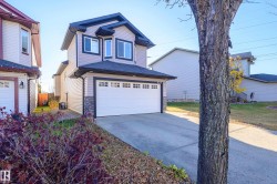 View of front of house featuring concrete driveway, stone siding, a garage, and a shingled roof - 