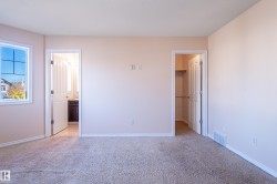 Unfurnished bedroom with a walk in closet, light colored carpet, and ensuite bath - 