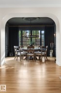 Dining area featuring arched walkways, ornamental molding, light wood-style floors, and a chandelier - 