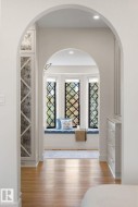 Hallway featuring healthy amount of natural light, arched walkways, and light wood-style flooring - 