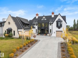 View of front of house with stone siding, concrete driveway, a garage, a front lawn, and a chimney - 