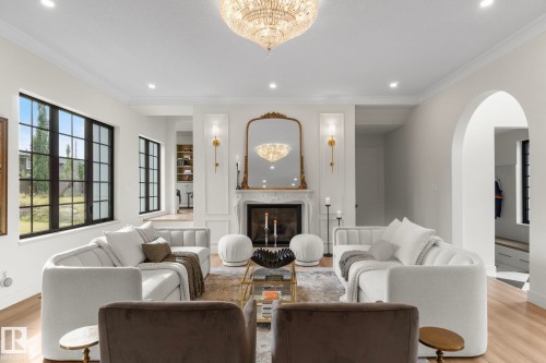 Living room featuring ornamental molding, a high end fireplace, wood finished floors, recessed lighting, and arched walkways - 183 Windermere Drive, Edmonton, AB - Indoor Photo Showing Other Room