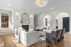 Living area with light wood-style floors, a high end fireplace, recessed lighting, ornamental molding, and a chandelier - 