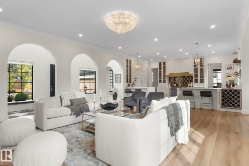 Living area featuring light wood-type flooring, ornamental molding, a chandelier, recessed lighting, and arched walkways - 183 Windermere Drive, Edmonton, AB - Indoor Photo Showing Living Room