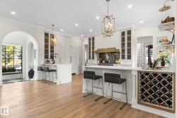 Kitchen featuring a breakfast bar, glass insert cabinets, a peninsula, white cabinets, and ornamental molding - 