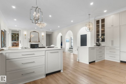Kitchen featuring open floor plan, white cabinets, a chandelier, crown molding, and pendant lighting - 183 Windermere Drive, Edmonton, AB - Indoor Photo Showing Kitchen With Upgraded Kitchen