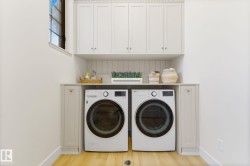 Laundry area featuring separate washer and dryer, light wood-style floors, and cabinet space - 