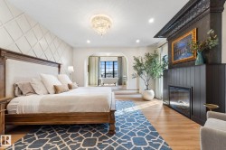 Bedroom with arched walkways, light wood-style floors, a glass covered fireplace, recessed lighting, and a chandelier - 