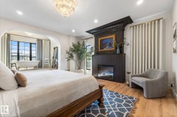 Bedroom featuring wood finished floors, arched walkways, a large fireplace, recessed lighting, and a chandelier - 