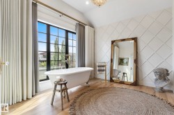 Full bathroom featuring wood finished floors, a soaking tub, lofted ceiling, and a chandelier - 