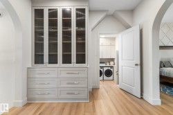 Walk in closet featuring arched walkways, light wood finished floors, and washing machine and dryer - 