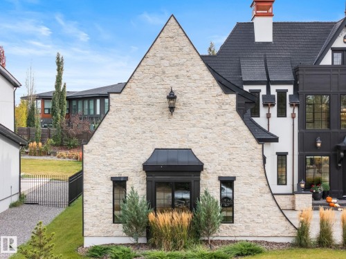 Rear view of property featuring stone siding and a chimney - 183 Windermere Drive, Edmonton, AB - Outdoor