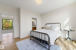 Bedroom featuring a chandelier, light wood finished floors, and ensuite bath - 